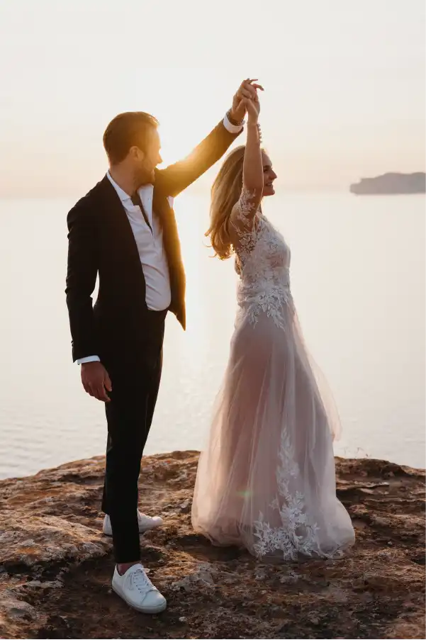 The newlyweds dance on a cliff at sunset after their wedding.