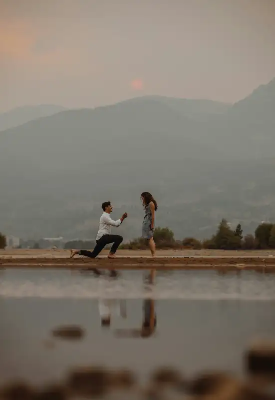 Romantic wedding proposal in Mallorca featuring a man on one knee proposing to his partner against a stunning mountain backdrop at sunset