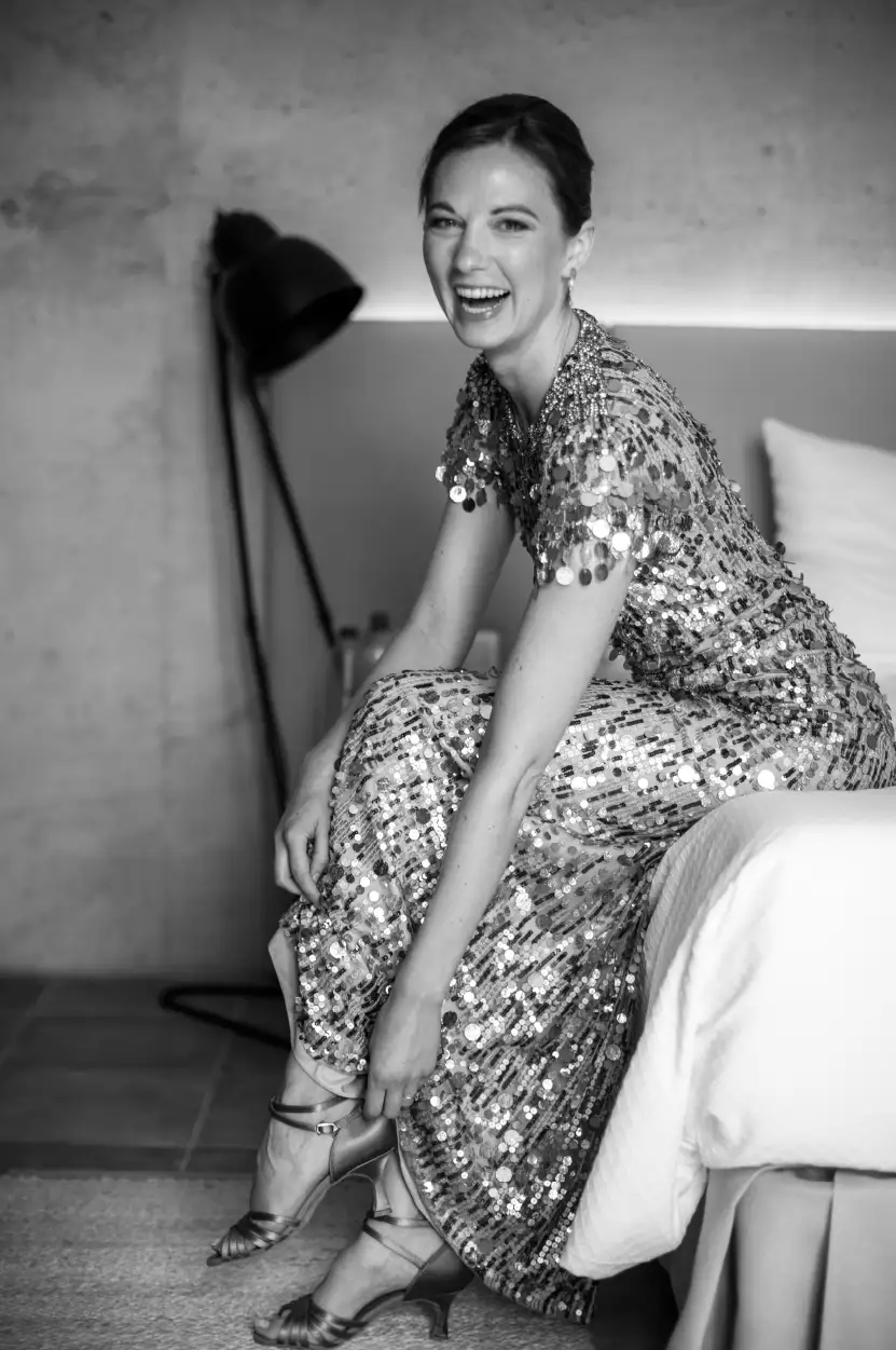 A joyful bride in a glamorous dress putting on her heels, preparing for her luxury wedding in Mallorca